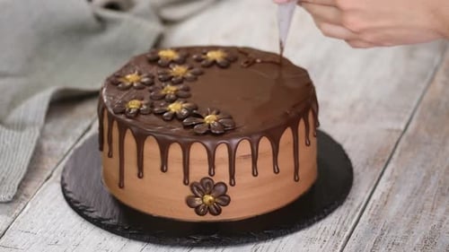 Confectioner-baker decorate beautiful cream cake with melted chocolate.
