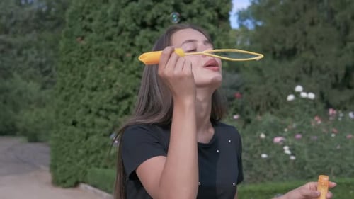 Woman Blowing Bubbles in a Park