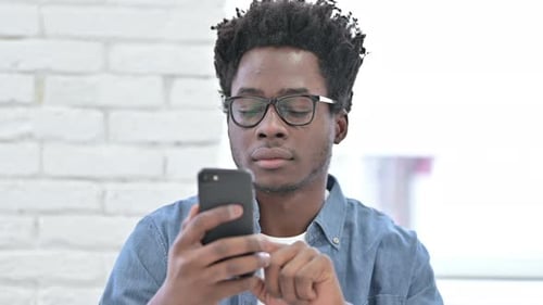 Man Celebrates Success on Smartphone Indoors