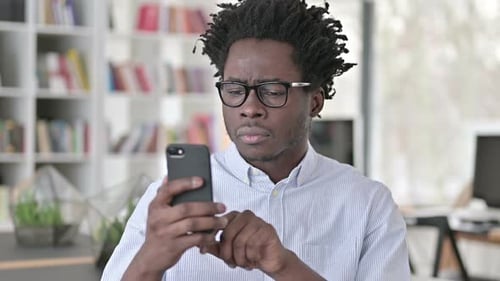 Frustrated Young Adult Using Smartphone Indoors