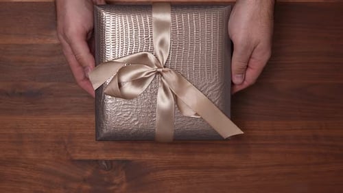 Hands Holding a Wrapped Birthday Gift with Ribbon