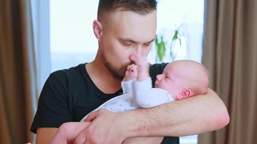 Young Adult Father Holding Newborn Infant Indoors