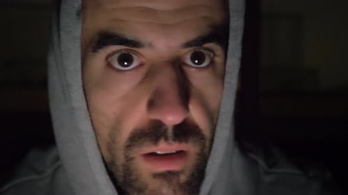 Spooky man whispering to camera and looking around scared