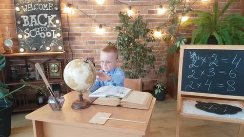 Young Boy Studying with Globe at Desk