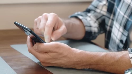 Manos de un hombre con un smartphone de cerca en la habitación