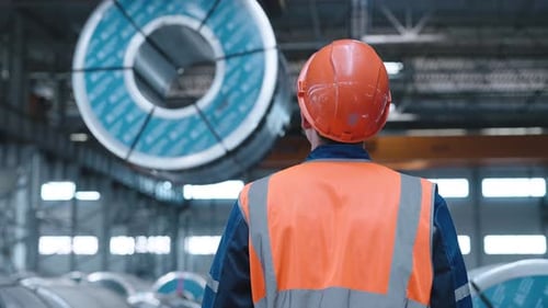 Un grutier en activité est engagé dans le chargement de produits métalliques laminés dans une entreprise ou un entrepôt