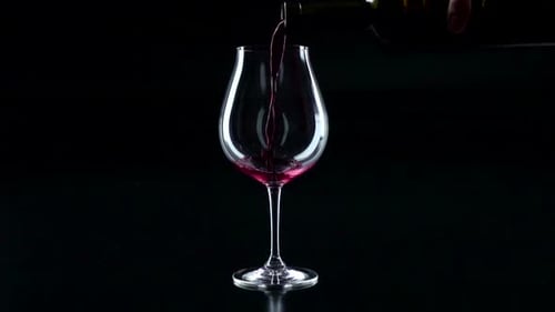 Red Wine Poured into Glass on Black Backdrop