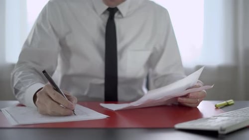 Adult Reviews Paperwork at Office Desk