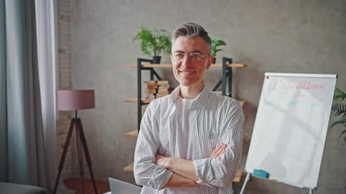 Smiling Man Standing in Home Office with Laptop
