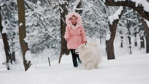 Girl Walks White Dog in Snowy Winter Park