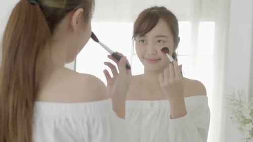 Woman Applying Makeup in Front of Mirror