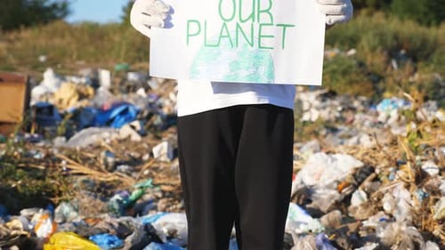 Young Person Holding Sign at Landfill