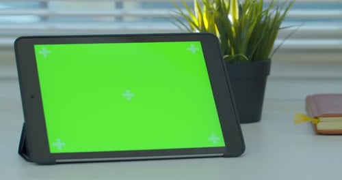 Black tabletPC on a Desk with Green Screen and Book. Close Up Footage.