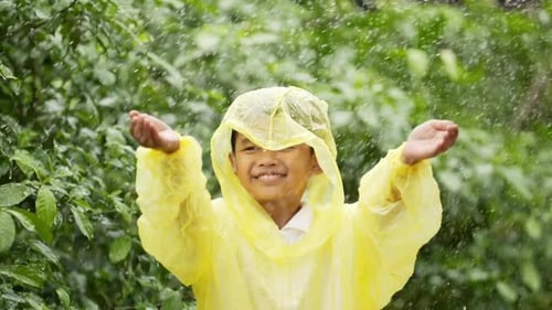 Happy Child in Raincoat Enjoys Rain