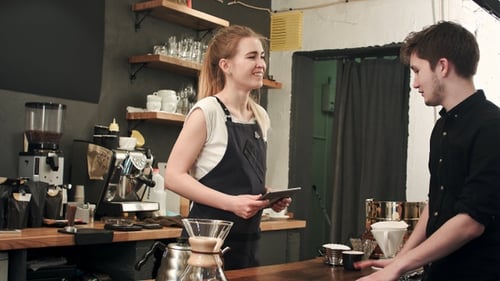 Male customer asking barista to make coffee in cafeteria