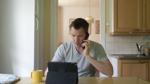 Man Using Tablet and Talking on Phone