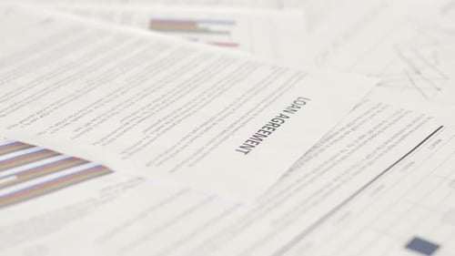 Loan Agreement Paperwork Scattered on a White Surface