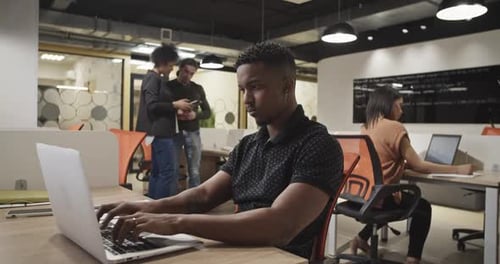 Focused Young Adult Typing in Modern Office