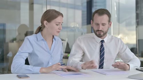 Professionals Discussing Business Documents at Modern Office Desk