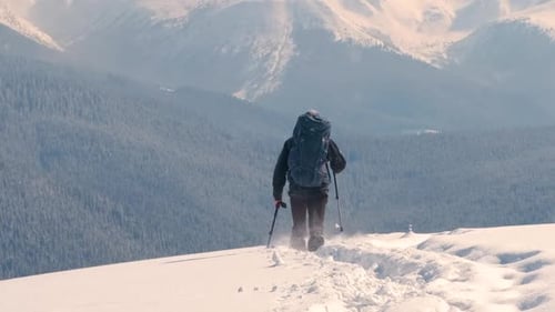 Man Backpacker Hiking Snowy Mountain Hillside on Cold Winter Day