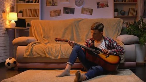 Teen Playing Acoustic Guitar at Home at Night