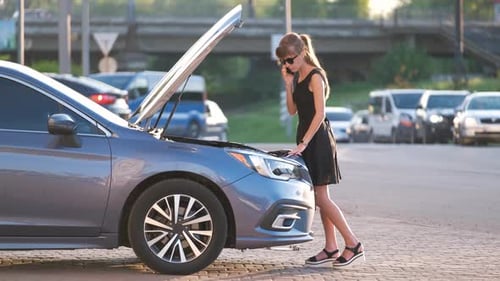 Helpless Woman Standing Near Her Car with Open Hood Takling on Mobile Phone Calling Road Service for