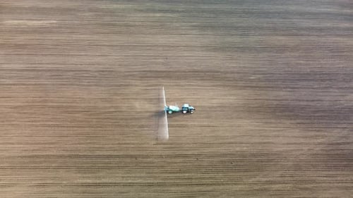 Tractor de vista aérea rociando semillas en campo terrestre