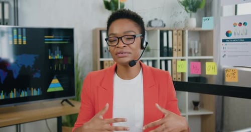 Empresaria afroamericana con auriculares que habla a la cámara durante un chat Vídeo