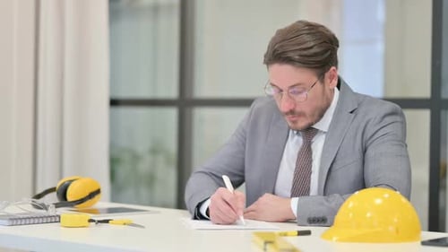 Ingenieur mittleren Alters schreibt im Büro auf Papier