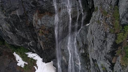 Aerial Of Fresh Winter Snow Melt Trickling Down Big Mountain Rock Cliff Face In Spring Season