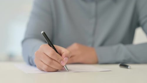 Nahaufnahme einer Afrikanerin, die mit Stift auf Papier schreibt