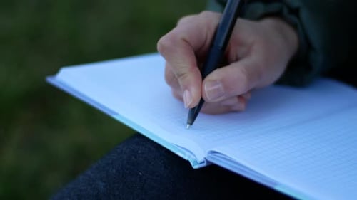 Hand Writes in Notebook with Pen Close Up