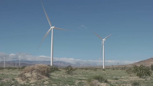 Large wind turbines spin and generate renewable electricity in a strong desert wind.