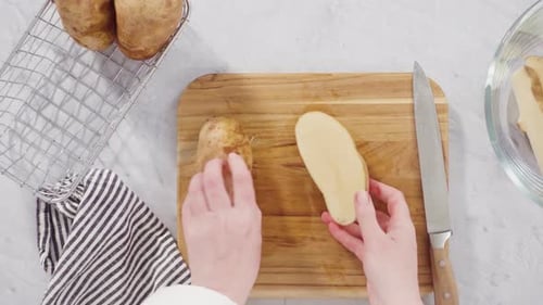 Time lapse. Flat lay. Step by step. Slicing russet potatoes in wedges with olive oil and spices to b