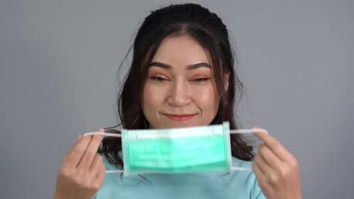 Woman Puts on a Disposable Face Mask