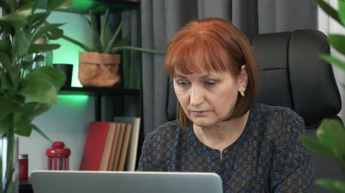 Portrait of attractive smiling woman is working on laptop computer at modern office workplace