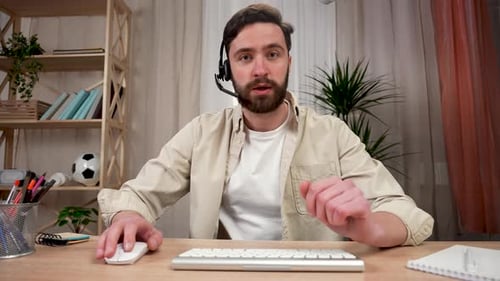 Man with Headset Talking and Typing at Desk