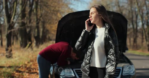 Woman on Phone with Car Trouble, Man Investigating