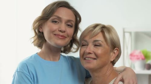 Adult Daughter Hugging Mother, Looking Into Camera, Love and Care of Relatives