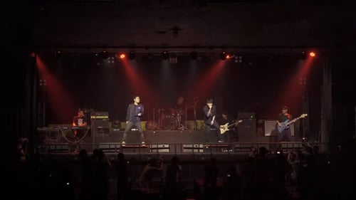 A singer with music band performing on a stage concert with lighting laser beam spotlight show