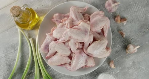 Trozos de alas de pollo crudos con ajo y cebolla rotados.