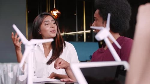 Young Adults Discussing Renewable Energy with Model Turbines