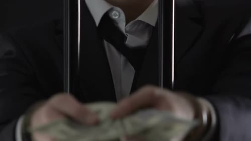Handcuffed Oligarch Standing Behind Prison Bars and Holding Money, Bribe Offer