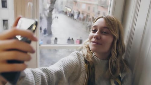 Young and Beautiful Girl Sitting in Cafe and Taking Selfies Blogger