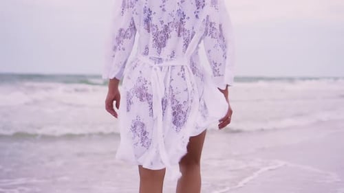 Girl Walks on the Beach on the Background of the Sea