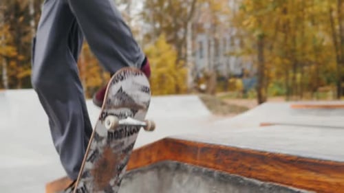 Skater Practicing in the Autumn Concrete Skate Park Making Tricks and Rides in Ramp