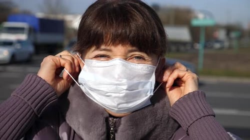 Senior Woman Putting On A Face Mask. Safety In Public Place During Coronavirus.