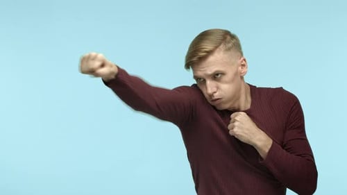 Handsome Blond Fit Man Sportsman in Casual Clothes Shadow Boxing Punching Air and Turn Face at