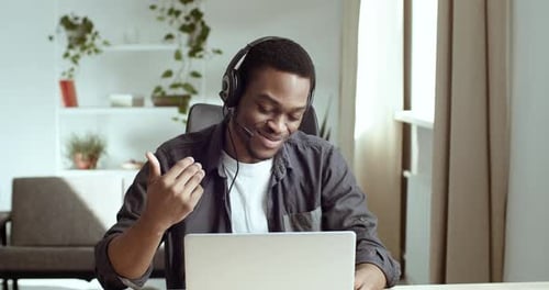 Man Communicating Online Via Laptop and Headphones