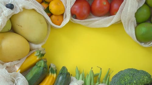 Colorful Fruits and Vegetables in Reusable Bags on a Yellow Background. Zero Waste. Reduce Plastic